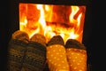 Feet in wool socks of couple lovers warming by cozy fire. Royalty Free Stock Photo
