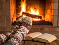 Feet in Wool Socks Near Open Book by Fireplace with Brick Background Royalty Free Stock Photo