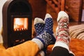 Feet in wool socks warming near fireplace in rustic cabin house. Cozy winter