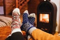 Feet in wool socks warming near fireplace in rustic cabin house. Cozy winter Royalty Free Stock Photo