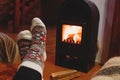 Feet in wool socks warming near fireplace in rustic cabin house. Cozy winter Royalty Free Stock Photo