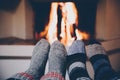 Feet in wool striped socks by the fireplace. Relaxing at Christmas fireplace on holiday evening Royalty Free Stock Photo