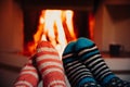 Feet in wool striped socks by the fireplace. Relaxing at Christmas fireplace on holiday evening Royalty Free Stock Photo