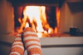 Feet in wool striped socks by the fireplace. Relaxing at Christmas fireplace on holiday evening