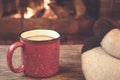 Feet in woolen socks, a red mug with hot tea opposite the burning fireplace, comfort, and warmth of the hearth concept Royalty Free Stock Photo