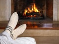 Feet in woollen socks and knitted plaid in front of the fireplace. Close up on feet. Cozy relaxed magical atmosphere home interior