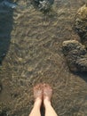 The feet of a young woman dipping into the sea