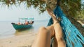 Feet of young woman lying on hammock at the sandy island beach Royalty Free Stock Photo