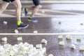 Feets of runners on marathon at service point, pile of used disposable white cardboard cups for beverages, blurred