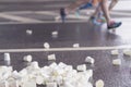 Feets of runners on marathon at service point, pile of used disposable white cardboard cups for beverages, selectiv