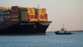 Container Ship being pulled into Felixstowe Port by Tug in early evening.