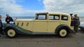 Beautiful Cream Coloured Classic Rolls Royce Motor Car parked on seafront promenade with beach and sea in background.