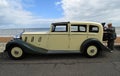 Beautiful Cream Coloured Classic Rolls Royce Motor Car parked on seafront promenade with man operating gramophone, beach and sea i