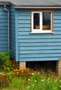 Blue cabin style dwelling with colourful flowers in bloom.