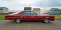 Classic Red Chrysler Newport 4 door Car parked on seafront Beach huts and sea in background. Royalty Free Stock Photo