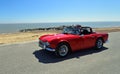 Classic Red Triumph TR4 Convertible Motor Car being driven along Seafront Promenade. Royalty Free Stock Photo