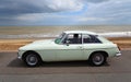 Classic Whie MGB GT Motor Car parked on seafront promenade with beach and sea in background. Royalty Free Stock Photo