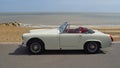 Classic White - Cream MG Midget Car parked on seafront promenade with sea in background.