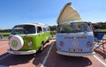 Two Classic VW Camper Vans parked in seaside car park.