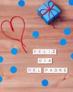 Feliz dia del padre words made of wooden blocks with blue gift boxes and red hearts on wooden background. Happy fathers day