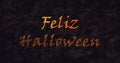 Feliz Halloween text in Spanish dissolving into dust to bottom