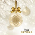 Feliz navidad - Christmas greetings in Spanish - patterned golden bauble with glitter gold bow hanging on a christmas tree.