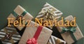 Feliz navidad text in orange over christmas gifts on green background