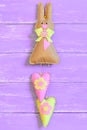 Felt Easter bunny decorated with bow, buttons and hearts isolated on purple wooden background. Easter bunny decor or gift idea