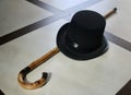 Image of a plain colored hat, made of felt with an imposing crown, narrow brim and matching decorative band and a cane.