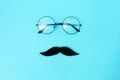 A felt moustache and eyeglasses on blue background with glasses. Top view. Concept of Father's day .