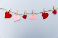 Felt red hearts pinned on a rope with clothespins on a blue background