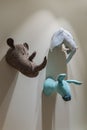 Felted animals toys hanging on the wall. Heads of donkey, rhinoceros and elephant on gray wall. Emulation of trophies