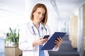 Femal doctor text messaging while standing in medical clinic