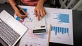 Female accountant using calculator and computer holding pen with financial graph and calculate home office expenses on top view ta