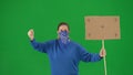 Female activist with face covered by scarf holding a blank poster. Female protester on green screen close up