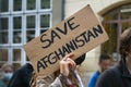 Female activist holding a cardboard sign with text Safe Afghanistan at a demonstration in Lubeck, Germany after the Taliban