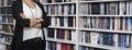 Female adult stands confidently in front of a tall bookcase