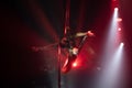 Female aerialist do stretching split on aerial silks with high heels backlit in red light. Face to the right