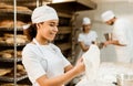 female african american baker kneading dough at baking manufacture while her colleagues working blurred