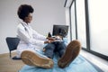 Female African American doctor gp pediatrician, in white coat palpating belly of teen child boy, lying on couch, smiling Royalty Free Stock Photo