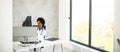 Female African American doctor wearing white coat with stethoscope sitting behind desk in office and looking x-ray image Royalty Free Stock Photo