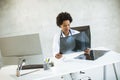 Female African American doctor wearing white coat with stethoscope sitting behind desk in office and looking x-ray image Royalty Free Stock Photo