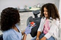 Female African doctor demonstrating proper dental care to her little kid patient, mulatto mixed raced schoolgirl. Happy Royalty Free Stock Photo