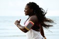 Female african runner jogging during outdoor workout on beach under rain