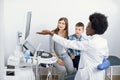 Female Afro American ultrasound doctor pointing at monitor of usg machine and explaining results of regular check up for Royalty Free Stock Photo