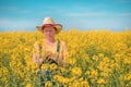 Female agronomist checking up on development of rapeseed crops in field, woman working on plantation