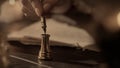 Female in antique outfit writes with feather pen. Close up shot of woman dipping vintage quill feather pen in golden Royalty Free Stock Photo