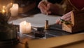 Female in antique outfit writes with feather pen. Focus on inkwell and box with spoons, woman in renaissance dress Royalty Free Stock Photo