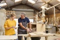 Female Apprentice Learning Skills From Mature Male Carpenter In Furniture Workshop Royalty Free Stock Photo