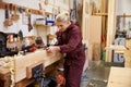 Female Apprentice Planing Wood In Carpentry Workshop